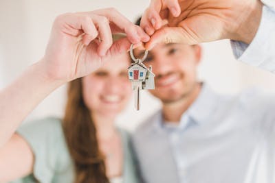 young first-time homebuyer holding keys to their new home.