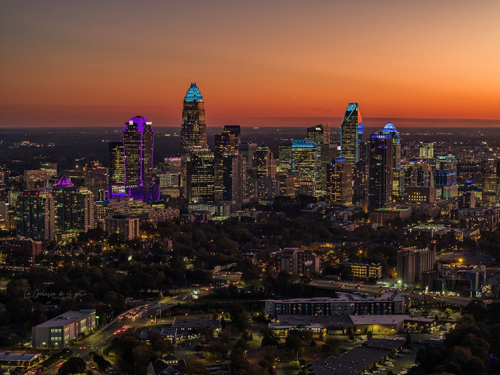 Aerial view of Charlotte cityscape with illuminated skyscrapers at twilight, showcasing growth in National Rankings.