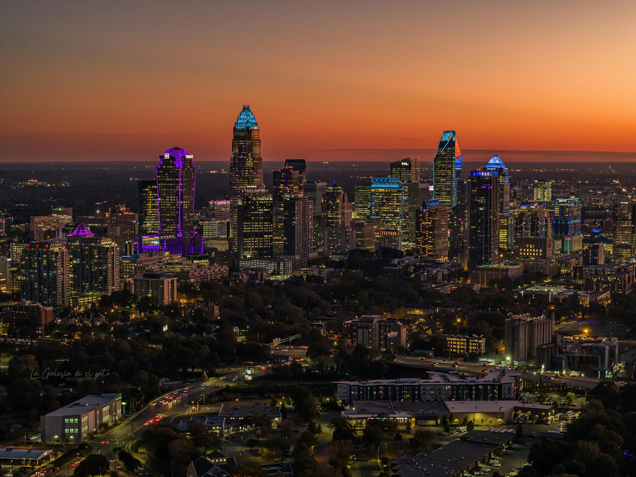 Aerial view of Charlotte cityscape with illuminated skyscrapers at twilight, showcasing growth in National Rankings.