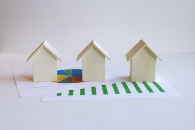 Wooden model houses on graphs depicting Arizona's sky-high rental prices on the rise.