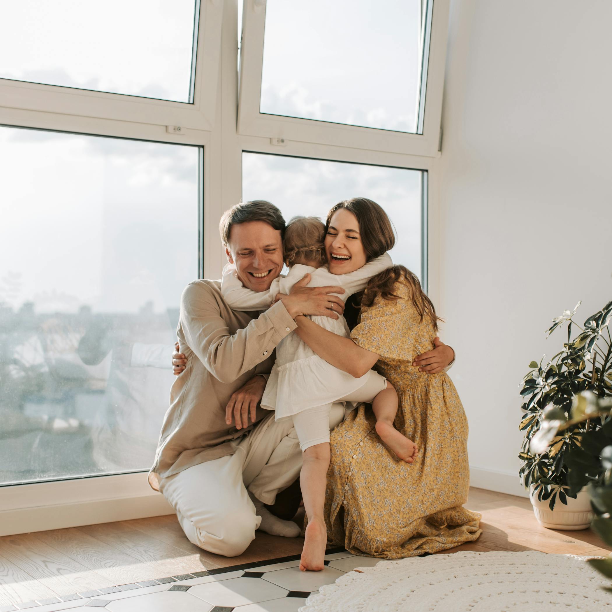 A joyful family hugging tightly near a window showcasing the demographic shift in the rental market with life milestones.