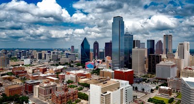 A stunning panoramic view of the Dallas skyline under dramatic clouds, capturing the city's iconic skyscrapers and showcasing America's Happiest City.