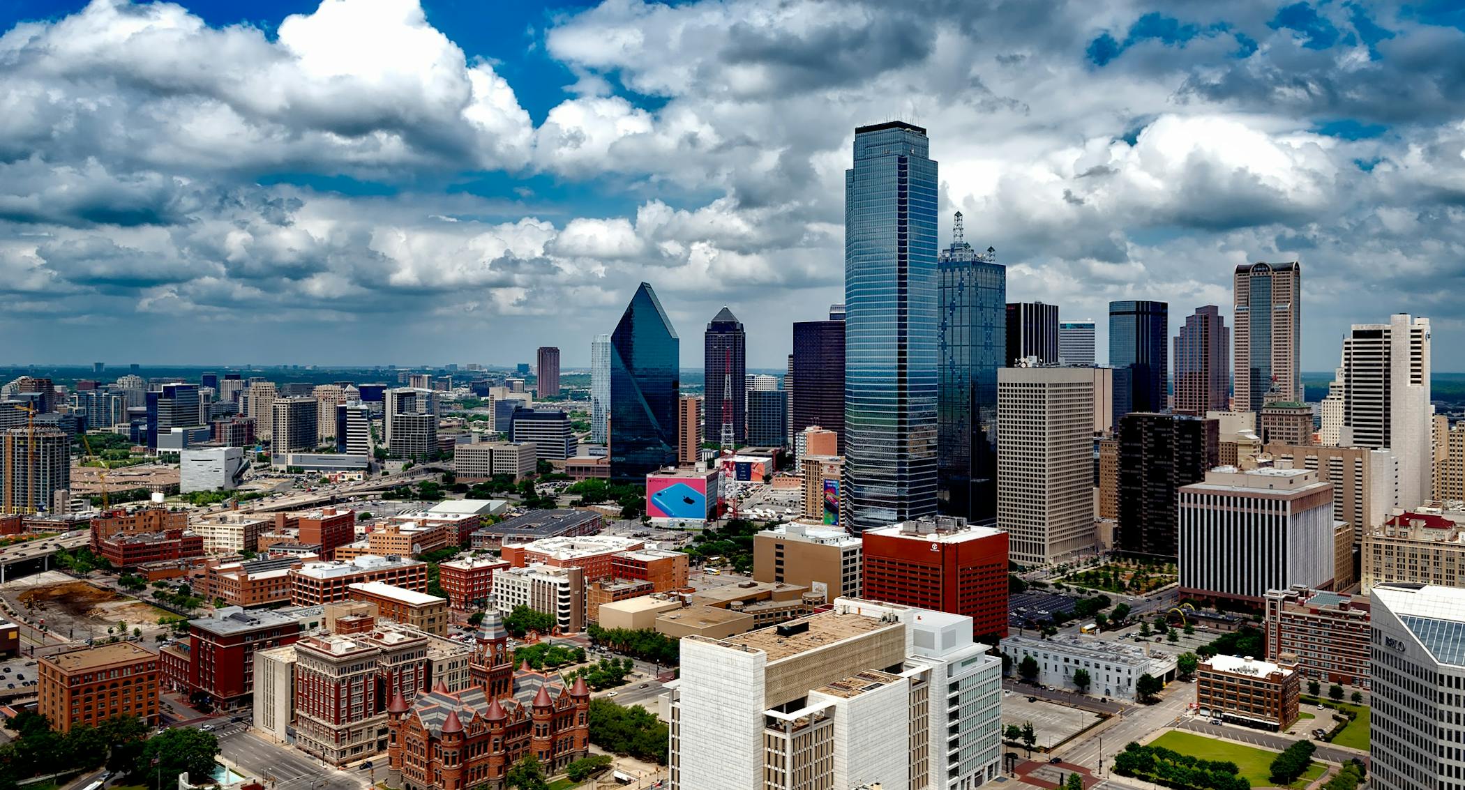 A stunning panoramic view of the Dallas skyline under dramatic clouds, capturing the city's iconic skyscrapers and showcasing America's Happiest City.