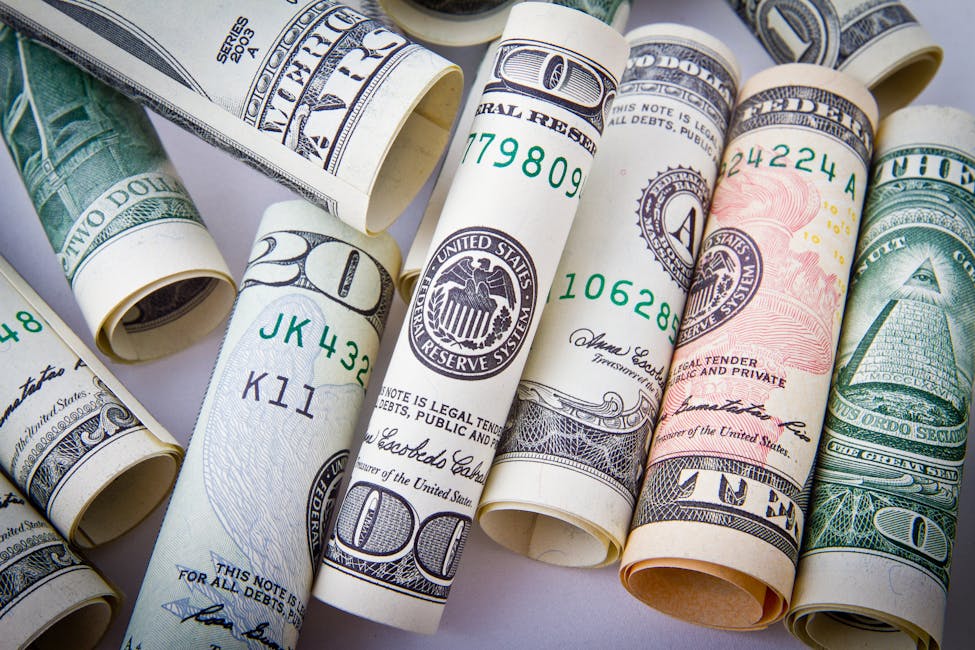 Close-up of rolled US dollar bills symbolizing the income a household needs to make to either buy a home or rent an apartment.