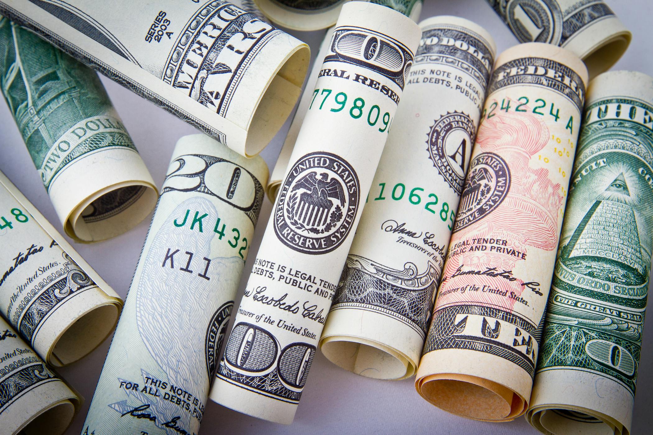 Close-up of rolled US dollar bills symbolizing the income a household needs to make to either buy a home or rent an apartment.