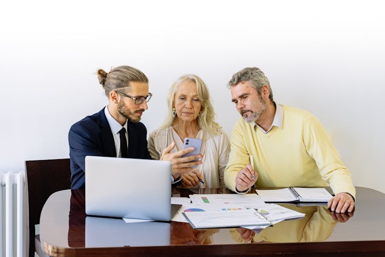 Three individuals collaborating on financial documents showcasing homeowners being reluctant to sell their home due to mortgage rates.