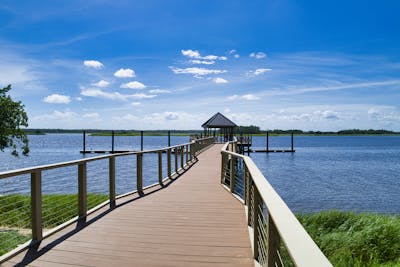 A serene pier over calm lake waters under a clear blue sky in Wilmington, NC showcasing the 6th ranked spot for best places for renters in 2025.