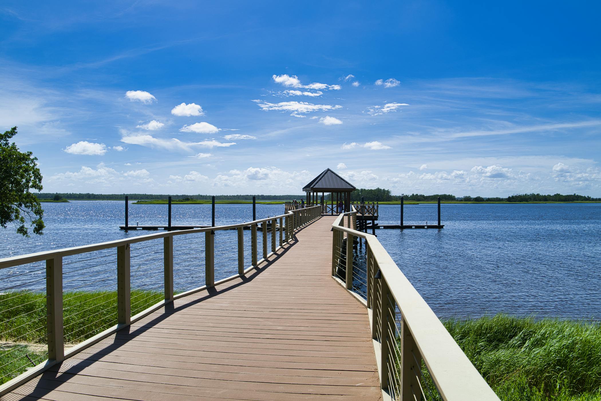 A serene pier over calm lake waters under a clear blue sky in Wilmington, NC showcasing the 6th ranked spot for best places for renters in 2025.