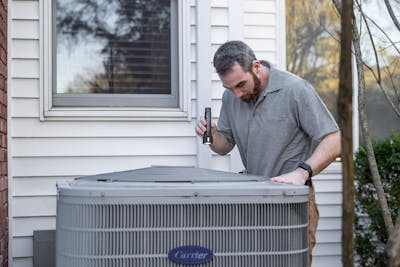 A technician inspects an outdoor HVAC unit for maintenance at a home in Raleigh, NC.