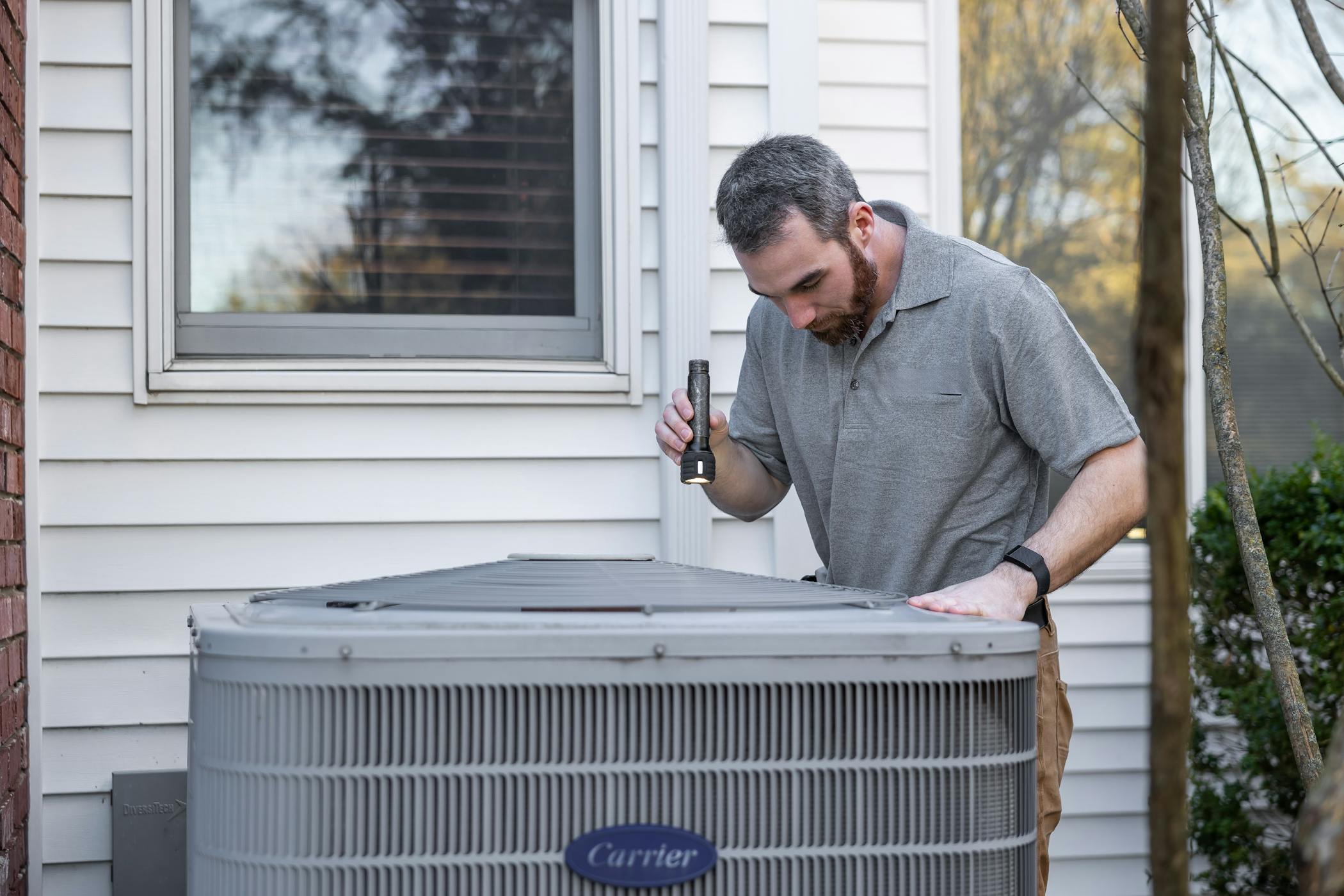 A technician inspects an outdoor HVAC unit for maintenance at a home in Raleigh, NC.