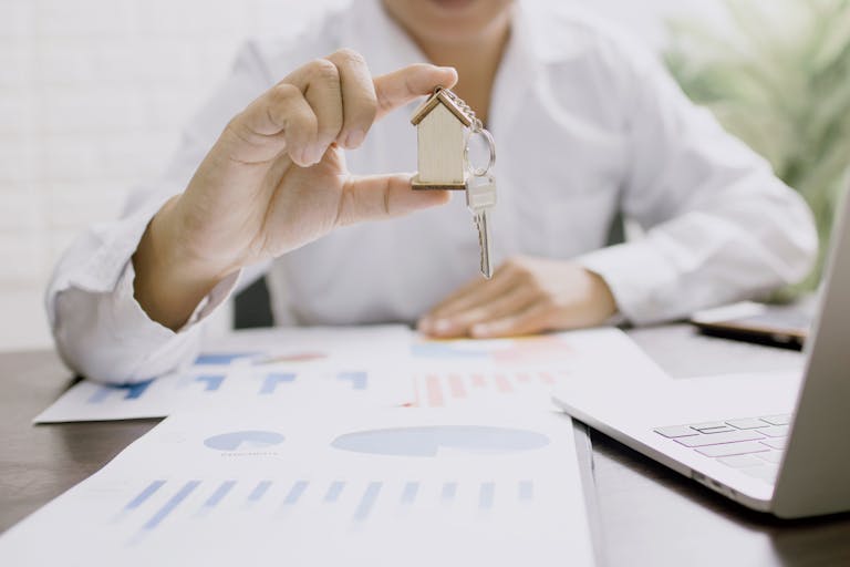 Real estate professional presenting a house model with keys, symbolizing the frustrations with landlords and selling their property.