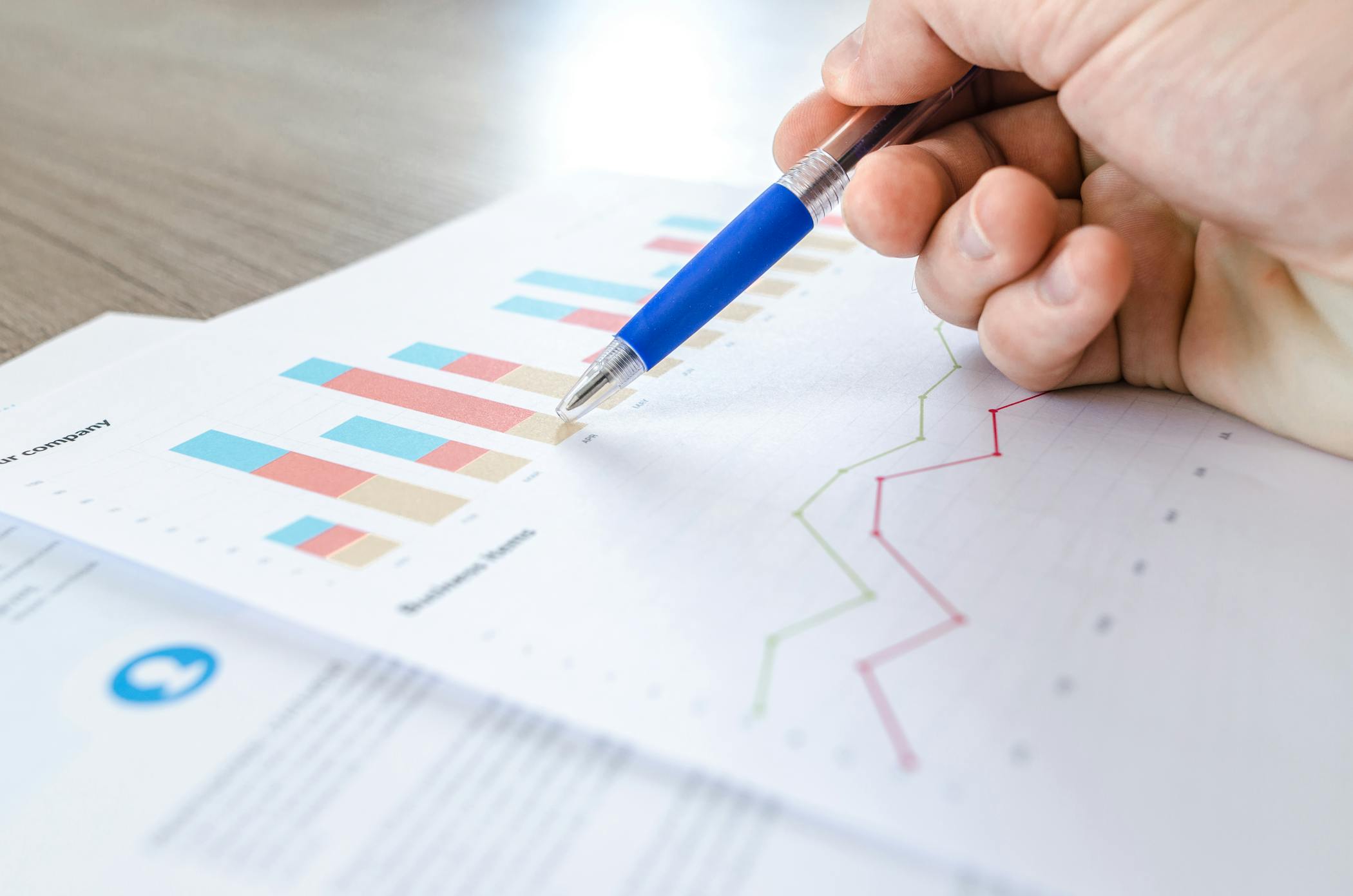 A close-up of a hand with a pen analyzing data on colorful bar and line charts on paper showcasing the numbers cooling down in the rental market.