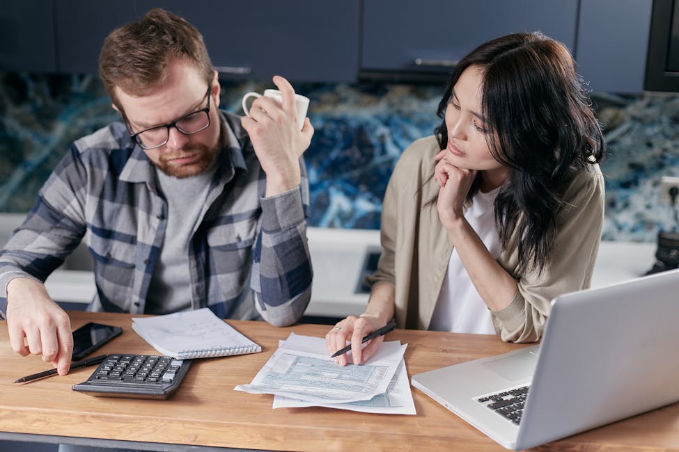 A couple reviews bills and documents on a laptop while discussing household finances showcasing why nearly half of home buyers have regrets.