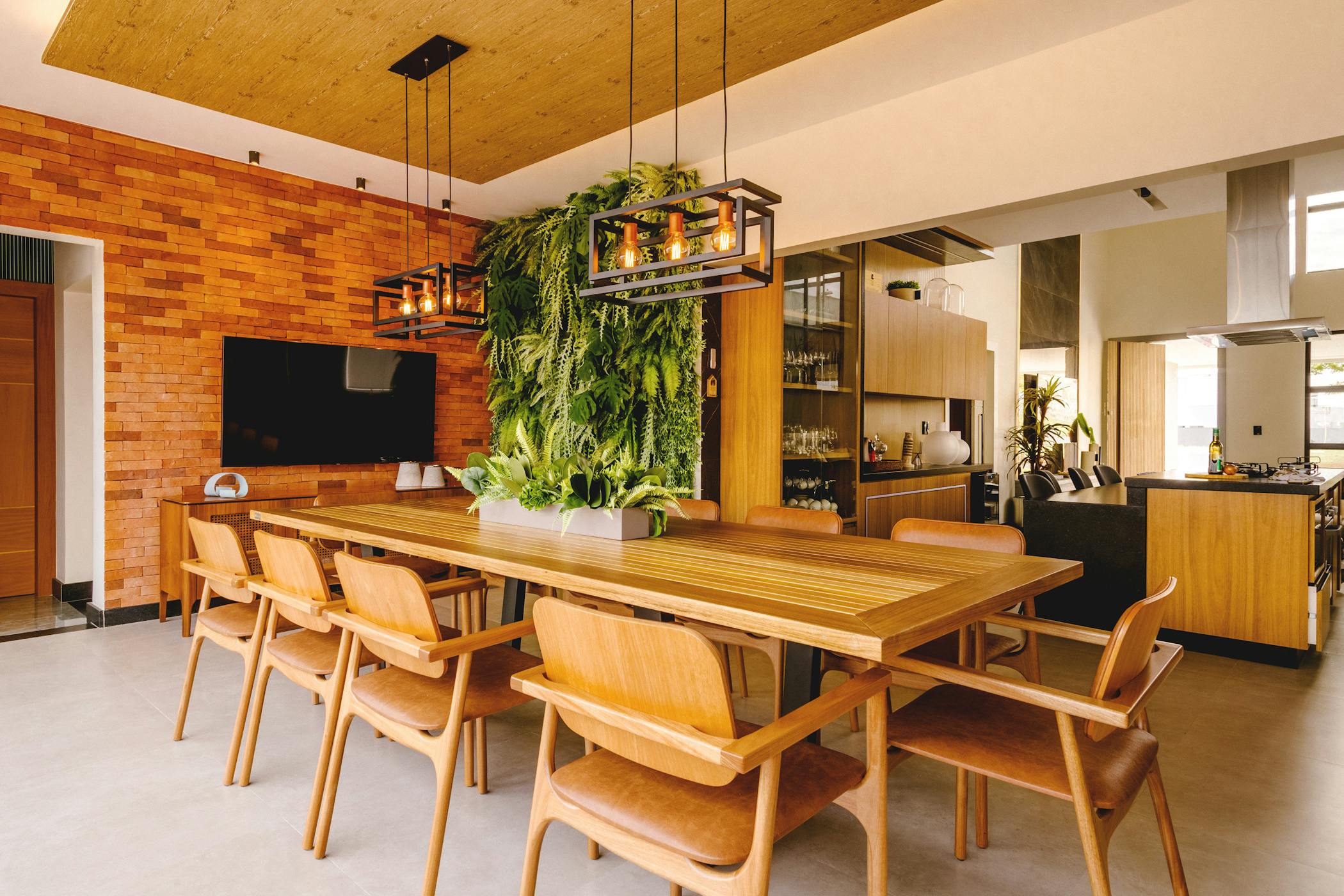 A stylish dining room featuring a wooden table, hanging greenery, and brick wall decor showcasing dining rooms are vanishing from modern homes.