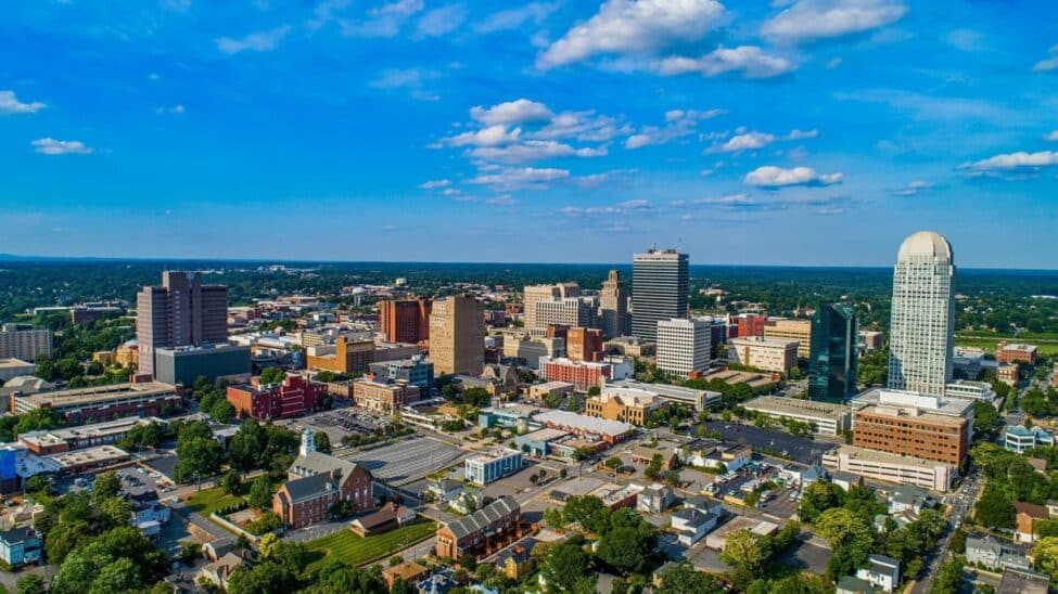 An aerial or elevated view of the Winston Salem's city skyline and urban architecture showcasing three major developments.