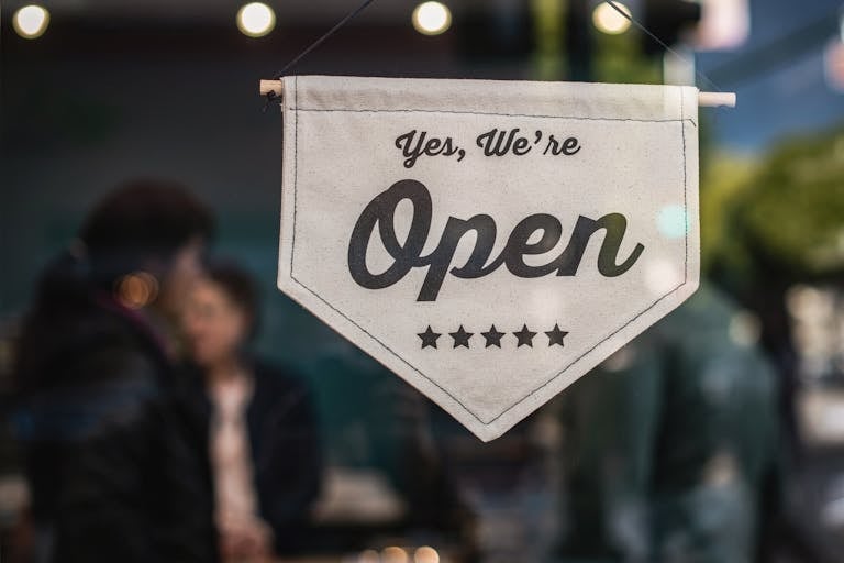 Welcoming open sign displayed in a shop window with blurred background showcasing a local business in Camp North End in Charlotte, North Carolina.
