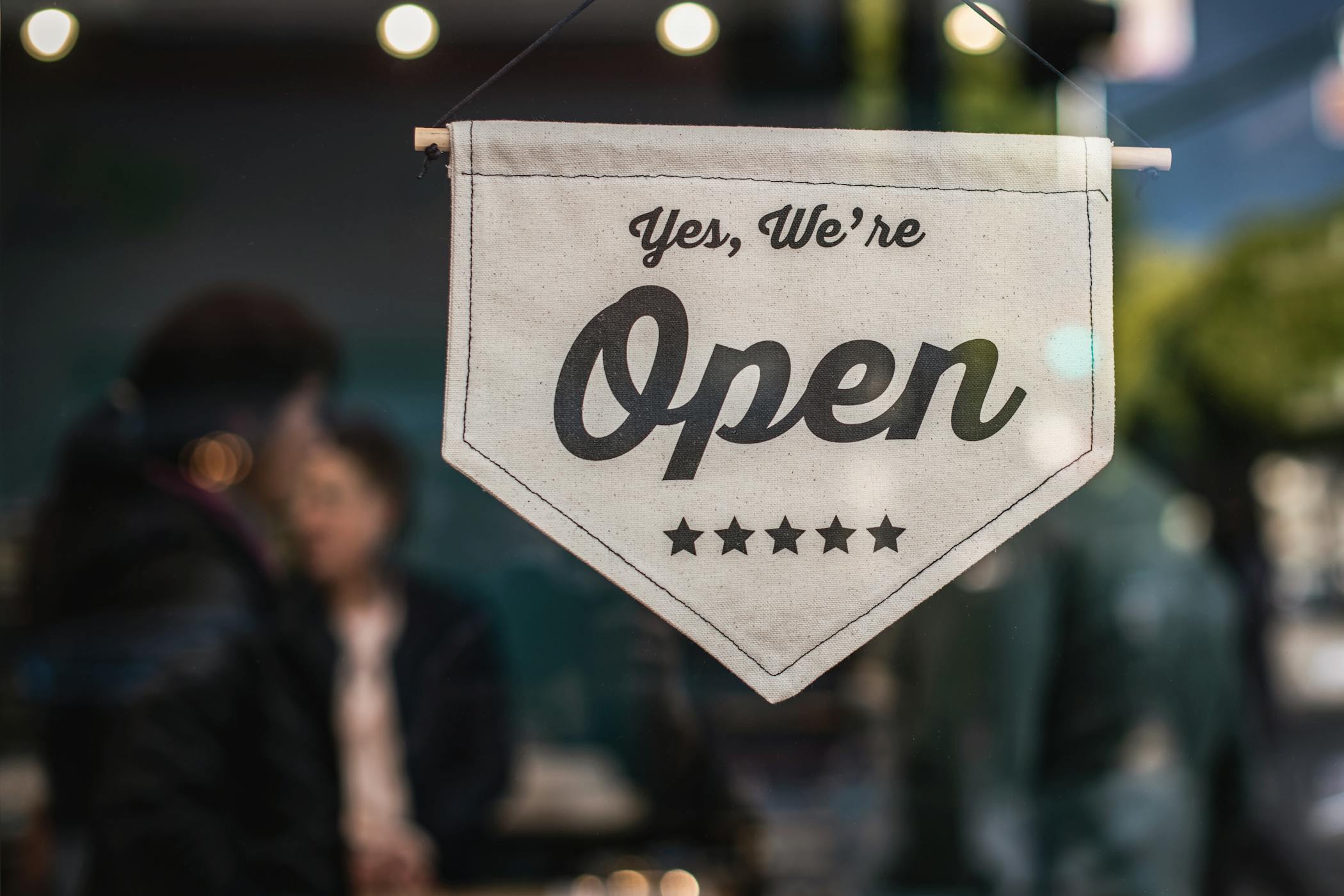 Welcoming open sign displayed in a shop window with blurred background showcasing a local business in Camp North End in Charlotte, North Carolina.