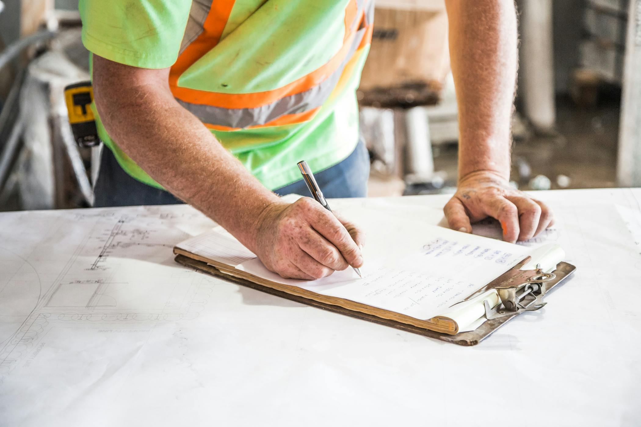 A construction worker writes notes on a clipboard at a construction site, emphasizing planning and precision showcasing Greenville County placing a temporary moratorium on a certain type of residential construction.