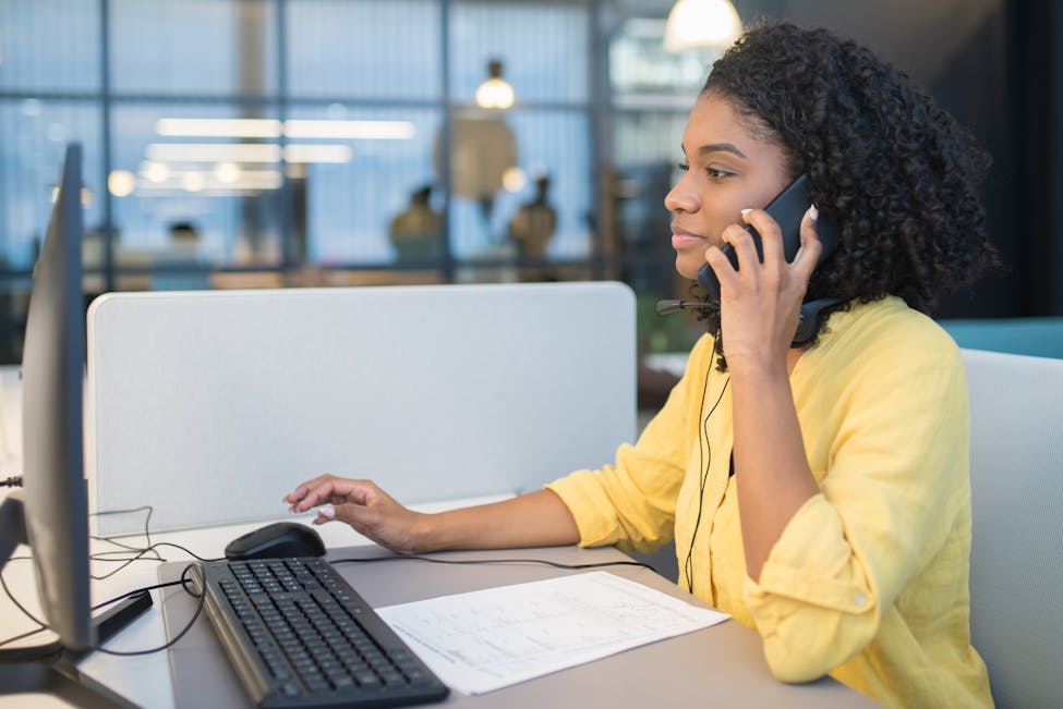 A young woman working in a modern call center environment, engaging in conversation showcasing our customers always interact with a human.