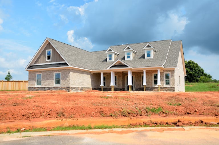 Brick modern family home under bright sky, showcasing new construction and architectural style showcasing the increase in unsold homebuilder inventory.