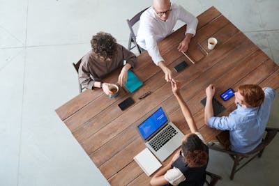 High angle view of a collaborative team meeting in an office setting with laptops showcasing the importance of entrepreneurs for the housing crisis.