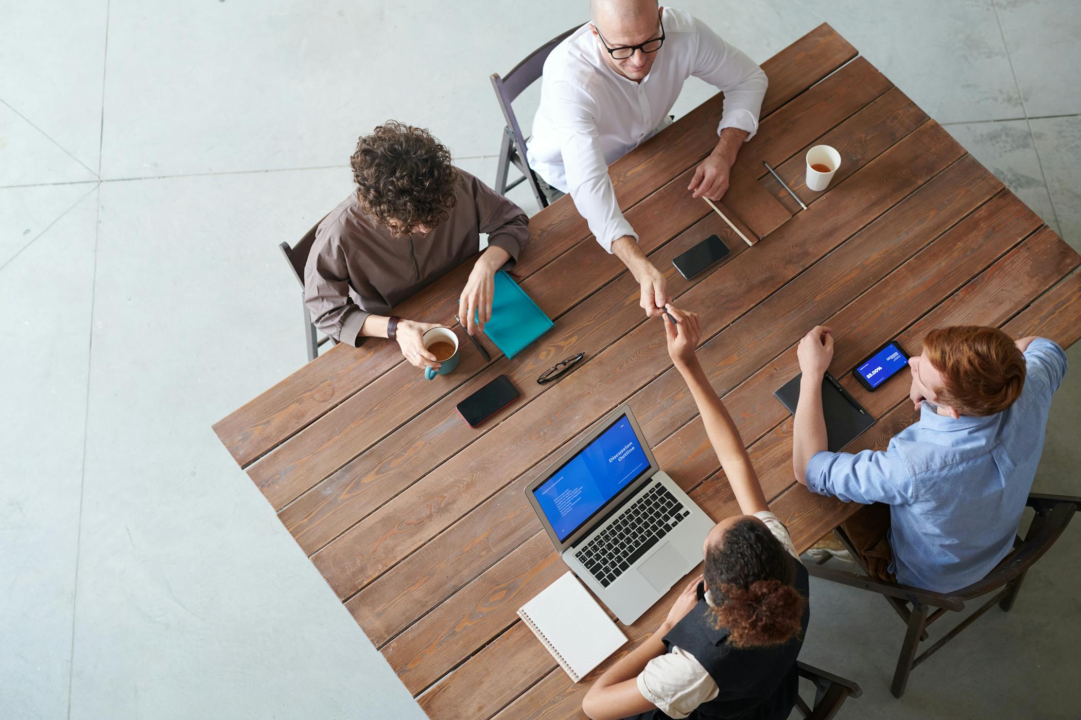 High angle view of a collaborative team meeting in an office setting with laptops showcasing the importance of entrepreneurs for the housing crisis.