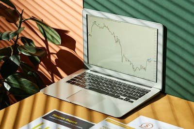 Laptop displaying a financial graph with reports, in a sunlit workspace showcasing the warm-weather cities who are leading rental market declines.