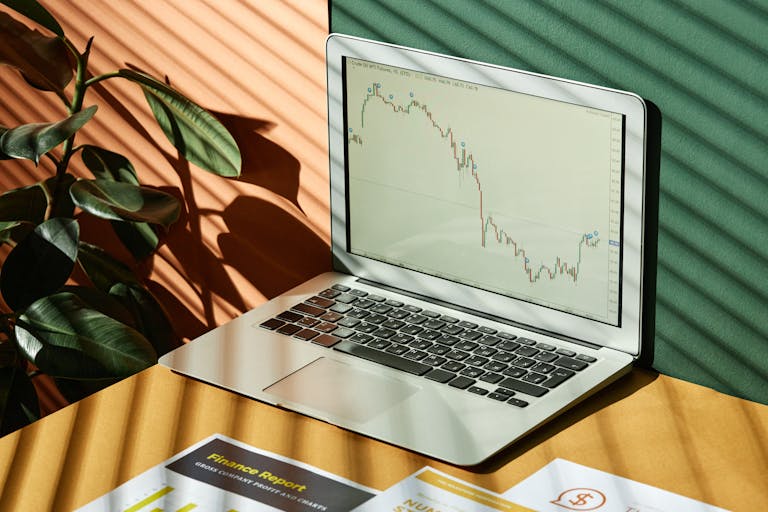 Laptop displaying a financial graph with reports, in a sunlit workspace showcasing the warm-weather cities who are leading rental market declines.