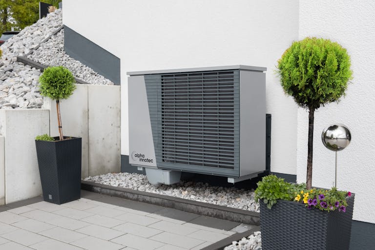 Modern air conditioning unit with flower pots and sleek decor outdoors showcasing owner mistakes that are costing them money with HVACs.
