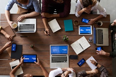 Overhead view of a diverse team in a business meeting using laptops and tablets showcasing North Carolina being good for businesses but not for workers.