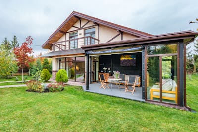 Residential cottage with balcony and opened veranda opening view on lawn and trees growing in backyard showcasing smart landscaping design for modern living.