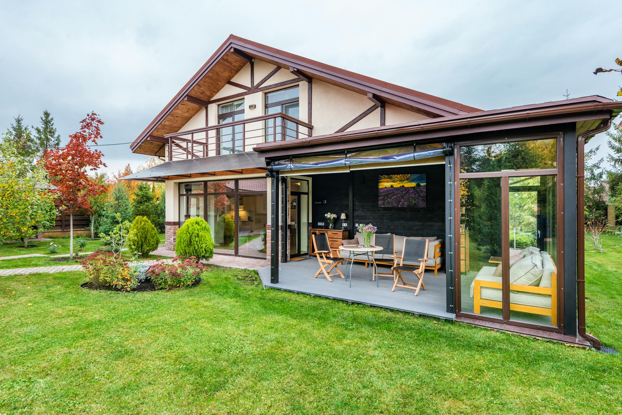 Residential cottage with balcony and opened veranda opening view on lawn and trees growing in backyard showcasing smart landscaping design for modern living.