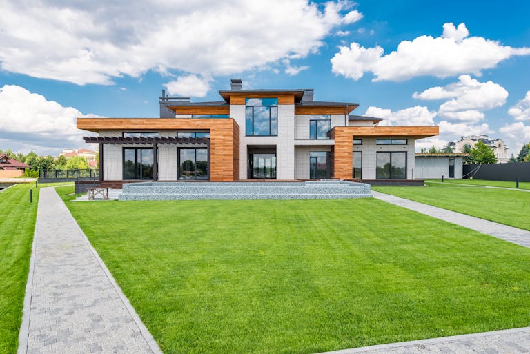 Stunning modern house exterior showcasing a spacious lawn and how turf is not the best solution for your landscaping.