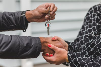 Close-up of a realtor handing over a house key to a new homeowner, symbolizing the new normal mortgage rate for 2026.