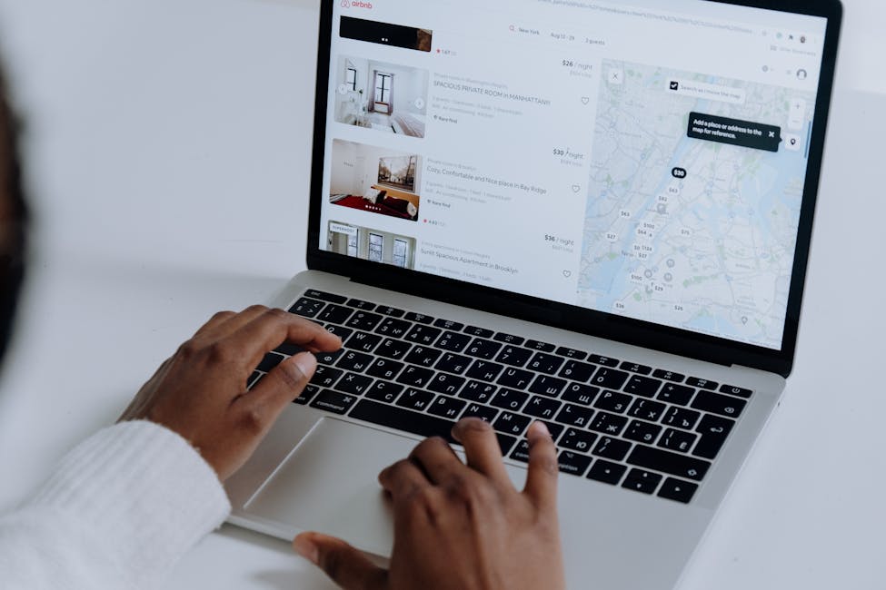 Hands typing on laptop searching properties showcasing how AI can enhance property listings for a better online presence.