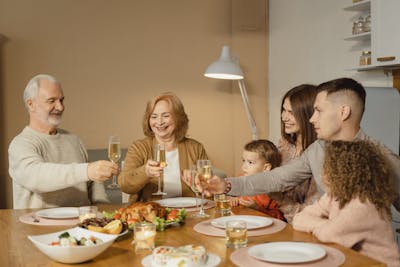 A joyful family toasts together over a festive dinner showcasing passing down of property to the next generation in the family.