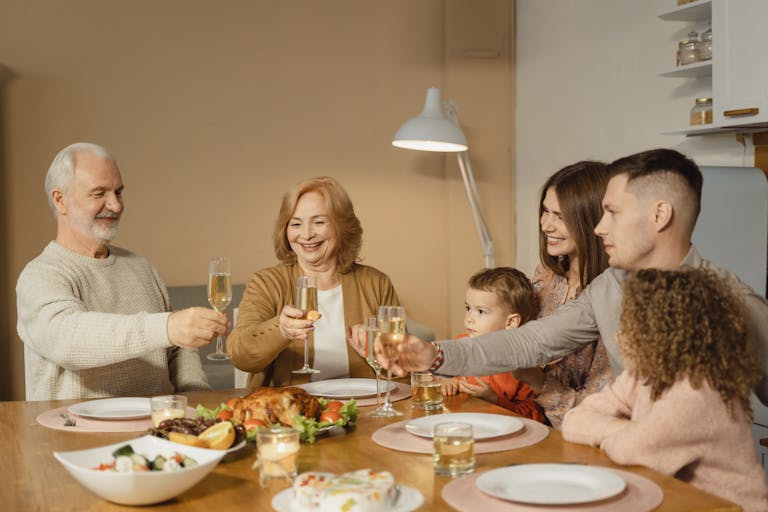 A joyful family toasts together over a festive dinner showcasing passing down of property to the next generation in the family.