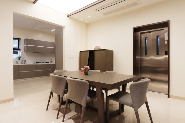 Contemporary dining area with table, chairs, and stylish kitchen view emphasizing the residential elevator that has been installed.