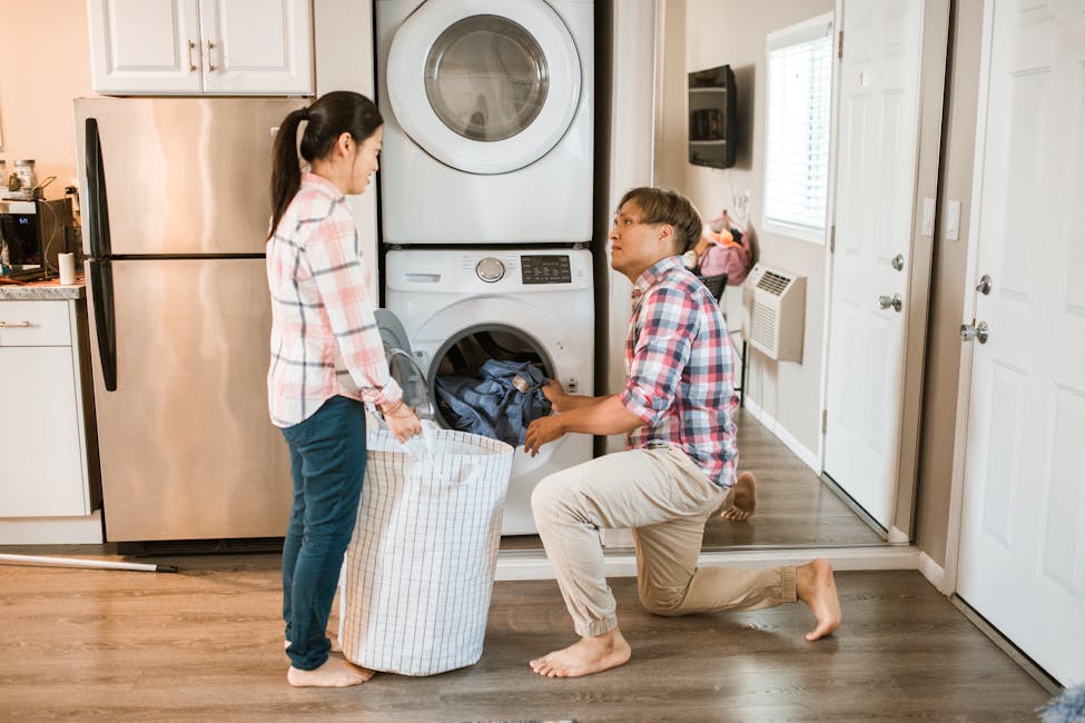 Couple managing household chores by throwing laundry in a washing machine that is provided by the owners of the rental property.