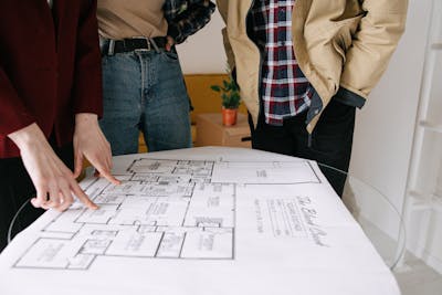 Group of people reviewing a blueprint for real estate planning showcasing the struggle new-home buyers may have when it comes to a quick resale.