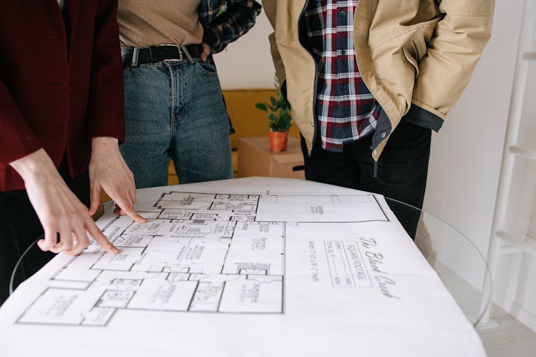 Group of people reviewing a blueprint for real estate planning showcasing the struggle new-home buyers may have when it comes to a quick resale.