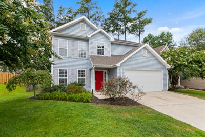 Charming suburban two-story house with a well-maintained lawn and vibrant garden showcasing a vacant home.