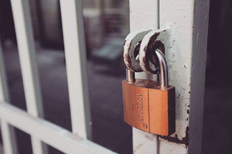 Closeup of a rusty padlock on a metal gate showcasing mortgage rate prison.