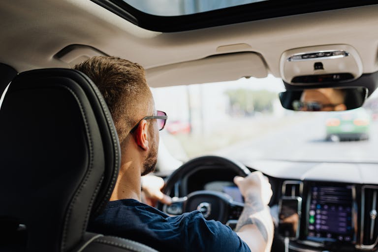 Rear view of a man driving a car with focus on interior details and steering showcasing driving on the new I-485 express lanes in Charlotte, North Carolina.