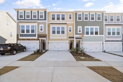 Symmetrical view of colorful modern townhouses with garages and driveways, showcasing contemporary architecture and multifamily housing.