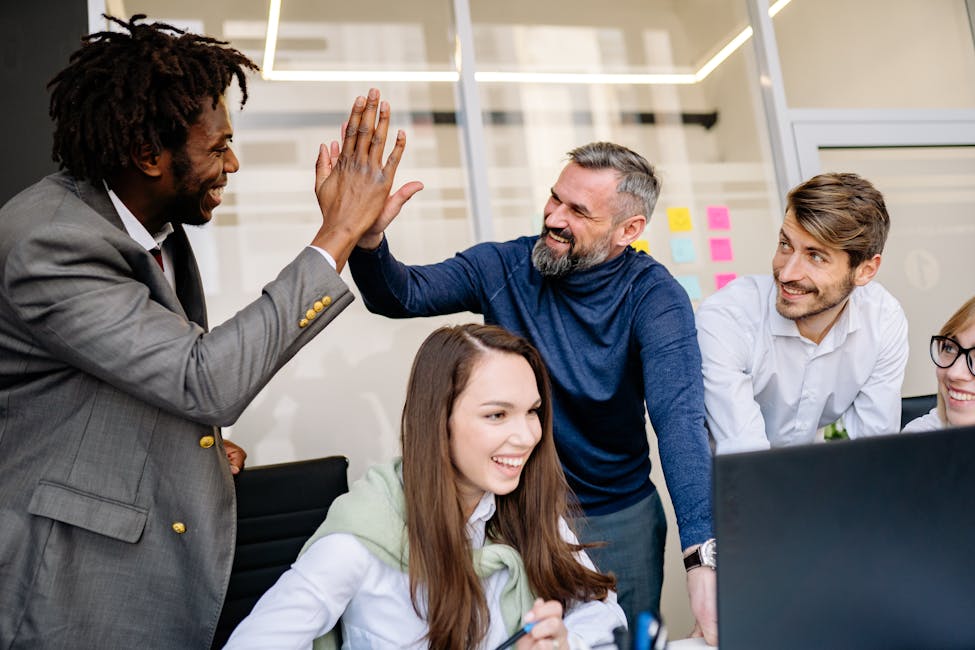 A diverse team happily celebrates a workplace achievement with high-fives showcasing the increase in jobs and what it means for rental investors.