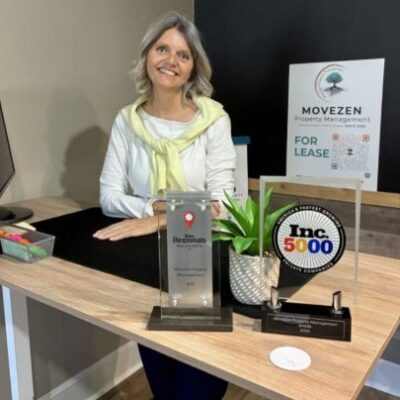 Catherine of MoveZen Property Management at her desk with the Inc. 5000 and Inc. Regionals award trophies