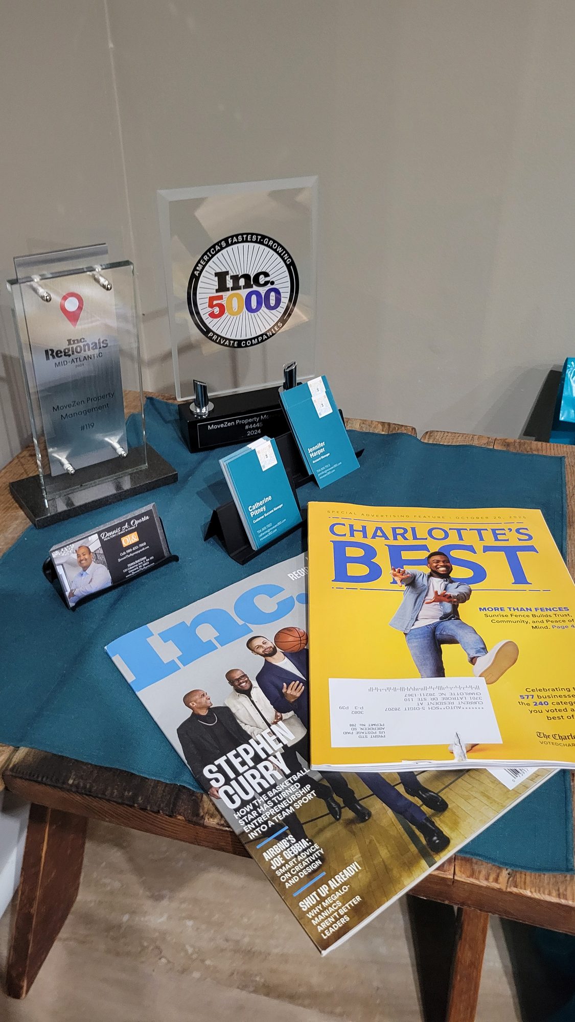 MoveZen Property Management award trophies with Inc. magazine and the Charlotte's Best 2025 issue of The Charlotte Observer