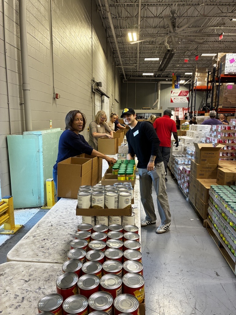 MoveZen volunteers packing canned food into boxes at the Second Harvest Food Bank warehouse in Charlotte NC